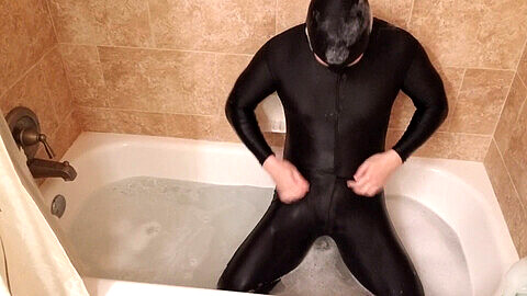 Hombre en látex disfruta de placer sin restricciones y se acaricia en un relajante baño de burbujas
