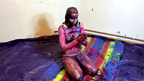 Una traviesa chica en forma se divierte con viscosos lodos coloridos y tartas de crema