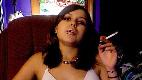 Rebelde fumadora sin sostén con piercings.