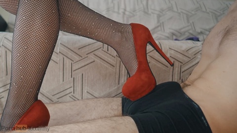 Seductive girl in red high heels gives a shoejob, tramples and receives a load of cum