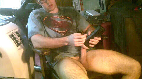 Clark Kent wichst seinen riesigen Schwanz, während er auf einem Stuhl sitzt